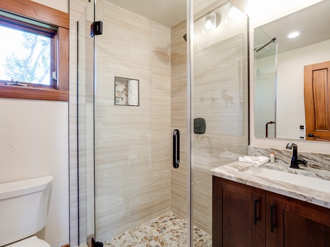 Elegant bathroom with glass-enclosed walk-in shower, marble-topped vanity, and warm natural light creating a serene spa-like atmosphere for your daily refresh.