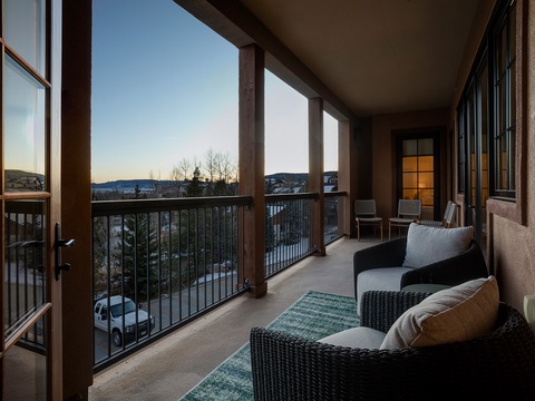 Your private balcony offers a serene mountain escape with comfortable seating to unwind and soak in stunning winter vistas as the sun sets over snow-dusted peaks.