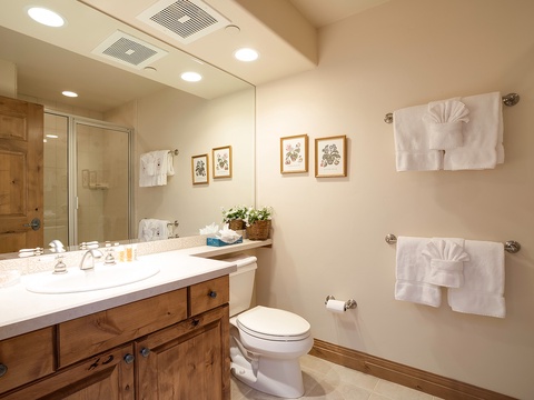 Step into your private bathroom with elegant botanical art, plush towels, and warm wood accents—a serene space designed for your comfort and relaxation.