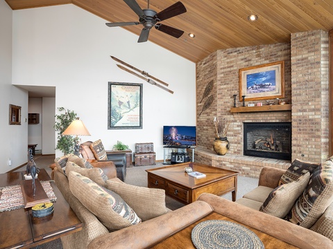 Relax in your inviting living room with soaring ceilings, warm wood tones, and a cozy fireplace—perfect for unwinding after your mountain adventures.
