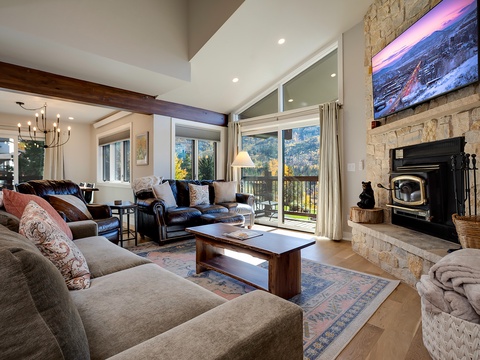 Unwind in this bright, open living space with soaring ceilings, plush seating, and a stone fireplace. Large windows frame stunning mountain views, inviting natural light into your cozy retreat.