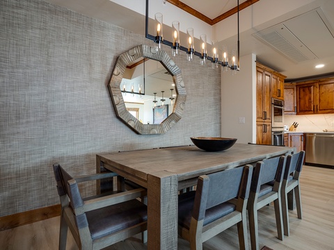 Gather around this handsome dining table for unforgettable meals under elegant chandelier light. The open-concept design flows seamlessly into your fully-equipped kitchen, perfect for entertaining.