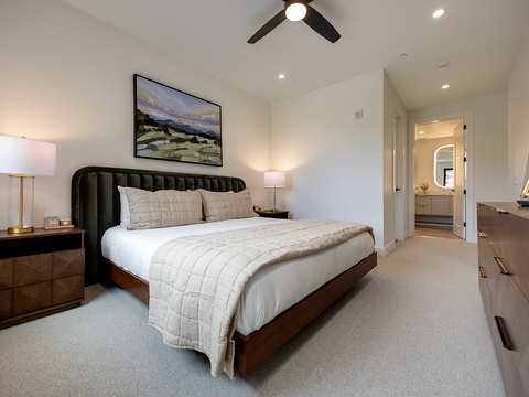 Sink into crisp linens and modern comfort in your serene bedroom retreat. The soft glow of bedside lamps and gentle ceiling fan create a peaceful ambiance where you can unwind after a day of exploring.