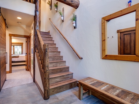 Your own private entrance opens to a stunning rustic staircase with reclaimed wood railings and charming wall planters, setting the tone for a cozy mountain escape.