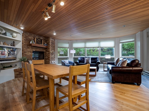 Settle into your inviting open-concept living space, where warm wood tones meet comfortable leather seating and abundant natural light streams through expansive windows, creating your perfect retreat.