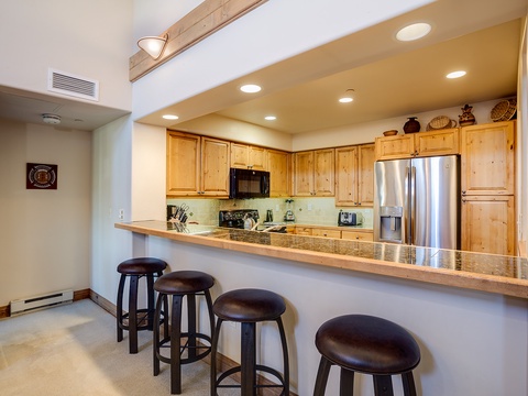 Your open kitchen features warm wood cabinetry, granite countertops, stainless steel appliances, and a breakfast bar with seating for four—perfect for casual meals together.