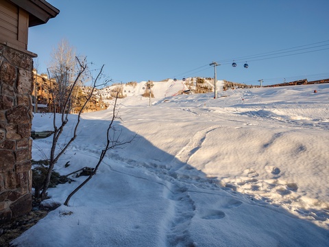 The property sits moments from premier ski slopes, with gondolas and ski lifts visible across snow-covered terrain—perfect for an adventurous winter mountain retreat.