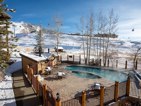 Heated pool and hot tub framed by snow-dusted trees offer front-row views of the ski slopes and gondola. Perfect for warming up after a day on the mountain.