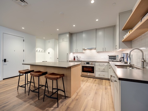 Your modern kitchen comes fully equipped with sleek appliances, a spacious island with seating, and open shelving to make meal prep a breeze.