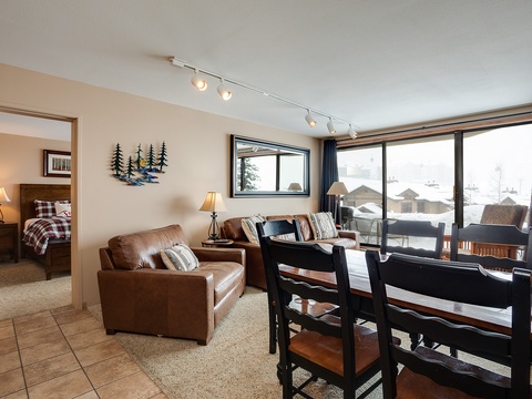 Picture yourself unwinding on the plush leather sofa, natural light streaming through expansive windows framing snowy mountain views, creating your perfect après-ski retreat.