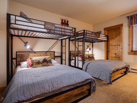 Your spacious bedroom features two custom bunk setups with cozy bedding, reading lights, and rustic wood accents—perfect for family fun and relaxation.