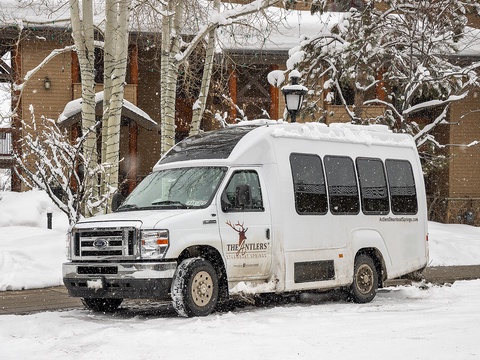 The Antlers shuttle stands ready in fresh snowfall, framed by frosted aspen trees and winter's quiet beauty near the property.