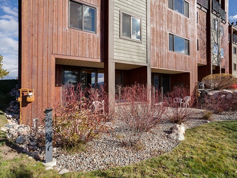 Modern multi-unit property featuring contemporary wood and neutral siding, surrounded by natural stone landscaping and seasonal plantings in a peaceful setting.