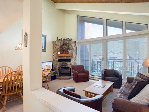 Unwind in your bright living room with a cozy stone fireplace, comfy seating for everyone, and mountain views just beyond the balcony doors.
