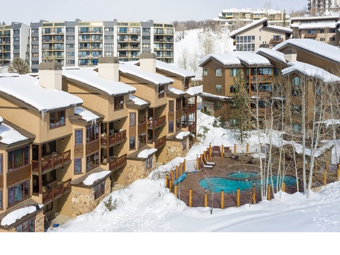 A snow-dusted mountain resort community featuring alpine-style lodges, modern condominiums, and a tranquil hot tub nestled among bare aspens—your winter retreat awaits in this scenic mountain village.
