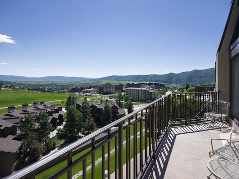 Spacious private balcony overlooks rolling green mountains, lush golf course, and charming mountain town—perfect for morning coffee or evening relaxation.