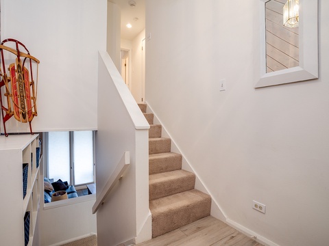 A bright hallway with carpet-lined stairs leads to upper levels, where charming touches like a vintage sled add character and welcome you to your alpine getaway.