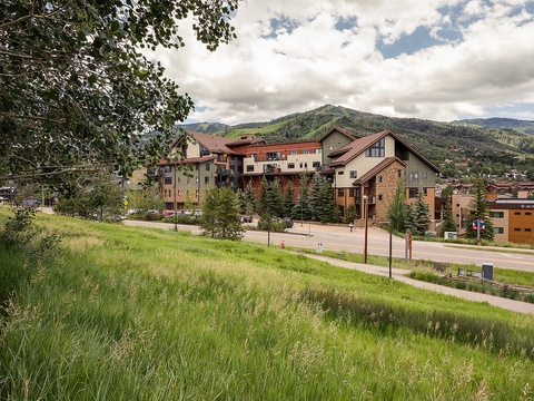 Mountain resort property nestled in lush valley with forested peaks rising majestically behind, offering a scenic alpine setting surrounded by natural beauty.