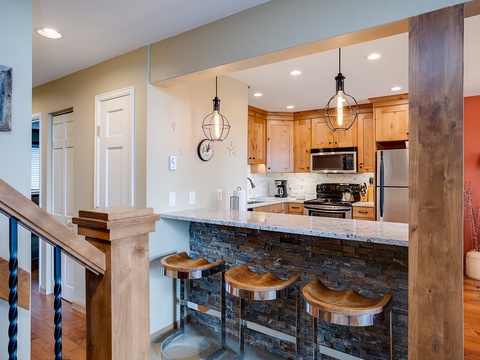 Your vacation kitchen features modern appliances, stylish pendant lights, and a gorgeous stone-front breakfast bar perfect for morning coffee or casual meals together.