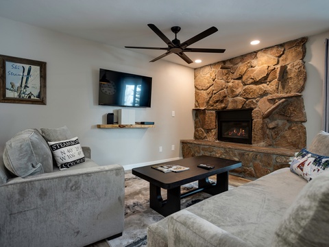 Sink into plush sofas and unwind by the warmth of the stone fireplace. Your cozy mountain retreat awaits, complete with modern entertainment and inviting charm.