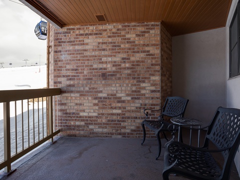 This covered balcony offers you a peaceful outdoor retreat, perfect for morning coffee or evening relaxation with inviting seating and classic brick charm.