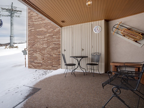 Cozy covered patio space with seating and mountain charm, offering a sheltered outdoor retreat just steps from the slopes.
