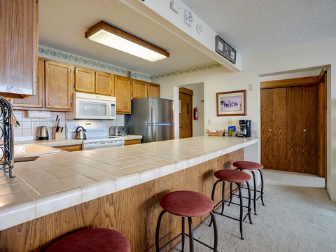 Gather around the welcoming breakfast bar with seating for four, perfect for morning coffee or casual meals. The full kitchen offers everything you need, from stainless appliances to ample counter space for preparing your favorite dishes.