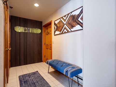 Step inside your welcoming entryway, where modern style meets mountain charm with warm wood accents, artistic touches, and a cozy bench perfect for gear and luggage.