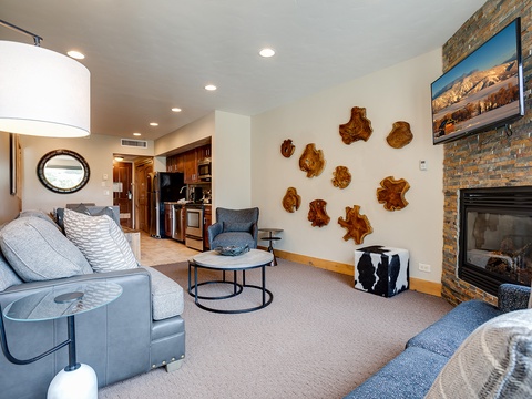 Cozy living space with stone fireplace, mountain art, and plush seating invites you to unwind after your day exploring.