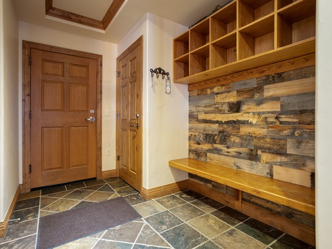 Step into your mountain retreat where rustic wood and stone blend seamlessly. Store your gear in custom cubbies and settle onto the bench—your adventure starts here.