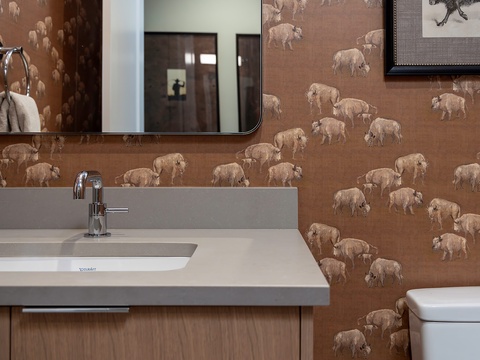 Charming bison-themed wallpaper and wildlife art bring the frontier spirit into your bathroom, paired with sleek modern fixtures and plush towels for comfort.
