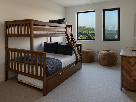 Wake up to sweeping natural landscape views from your bunk room, where cozy beds and textured seating invite you to relax after a day of exploring nearby adventures.