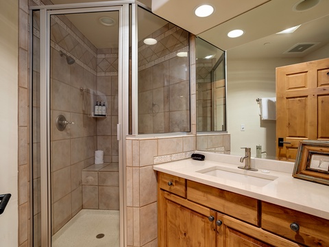 Step into your private spa-like bathroom featuring warm wood cabinetry and a spacious tiled shower ready for your refreshing mountain retreat.