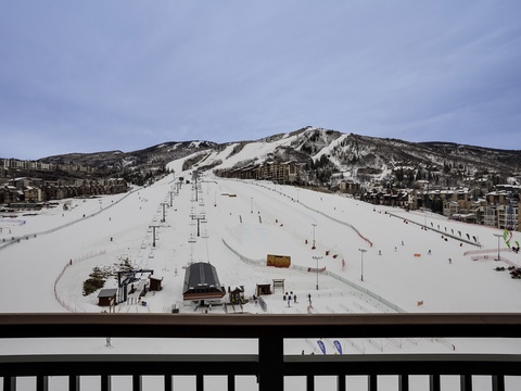 Sweeping ski slopes and mountain views frame this winter getaway, with ski lifts, runs, and a vibrant resort village visible from the balcony.