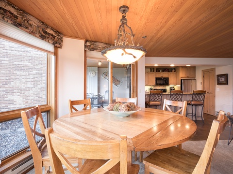 Gather around this inviting dining table where your mornings begin with coffee and your evenings end with laughter, all under a warm wood ceiling and just steps from your fully-equipped kitchen.