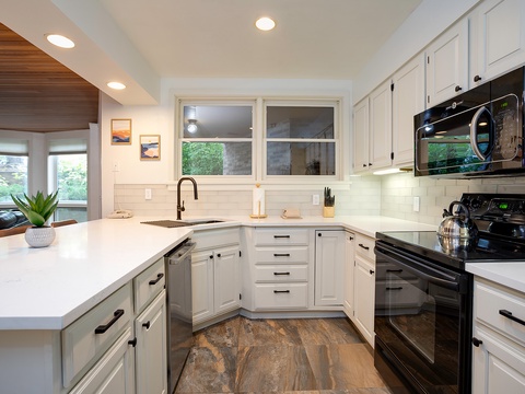 This bright, modern kitchen is ready for your culinary adventures. Enjoy crisp white cabinetry, gleaming countertops, and full appliances with natural light streaming through garden-view windows.