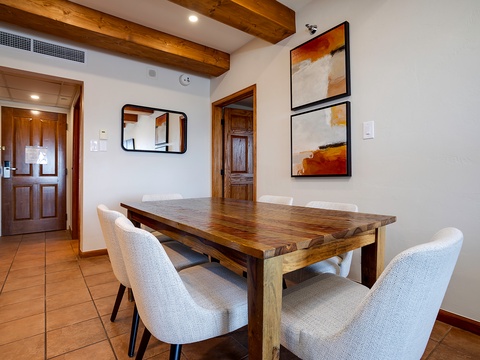Gather around the handcrafted wooden table for meals and memorable conversations under warm exposed beams. Modern comfort meets rustic charm in your inviting dining space.