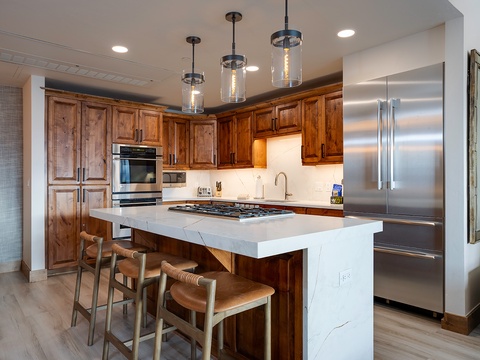 Picture yourself preparing gourmet meals in this beautifully appointed kitchen, featuring rich wood cabinetry, gleaming stainless steel appliances, and a spacious island perfect for gathering with loved ones.