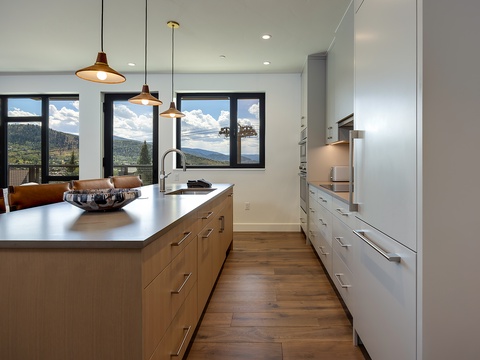 Your gourmet kitchen invites culinary creativity with sleek modern finishes, warm wood tones, and stunning mountain vistas through expansive windows that bring the outdoors in.