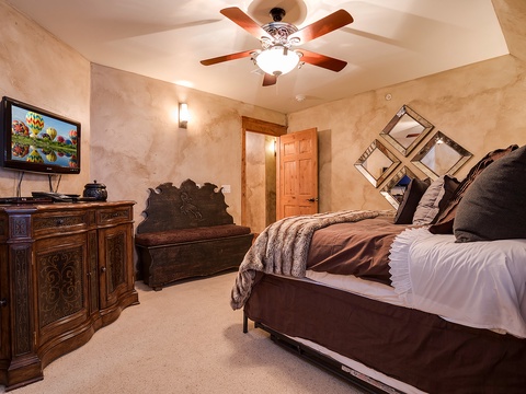 Sink into your plush bed under the soft glow of the ceiling fan, where elegant furnishings and warm textures create your perfect retreat after a day of adventure.