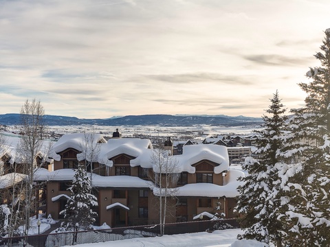 Snow-blanketed mountain resort property overlooking a serene winter valley with distant peaks on the horizon.