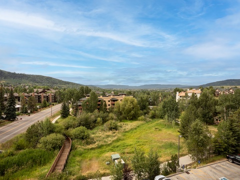 This property offers panoramic mountain views, nestled in a scenic area surrounded by rolling hills, lush greenery, and nearby residential buildings.