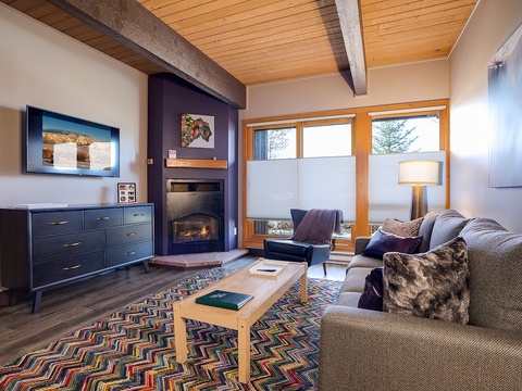 Sink into plush seating by your private fireplace, where warm wood tones and mountain light create your perfect retreat after a day of adventure.