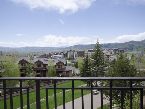 A mountainous area surrounds the property, with residential neighborhoods and larger buildings visible across the valley floor under a partly cloudy sky.