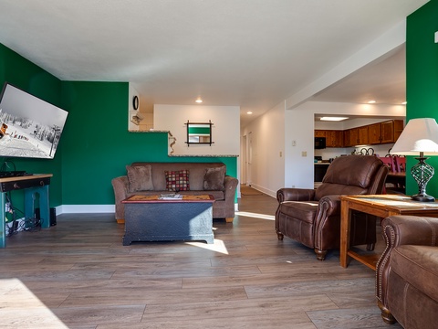 Settle into your spacious living area with vibrant green walls, rich leather seating, and warm wood tones creating a welcoming retreat after your mountain adventures.