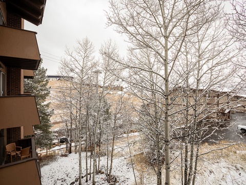 Scenic winter view from the property showcasing snowy grounds, bare trees, and nearby buildings in a peaceful mountain setting.