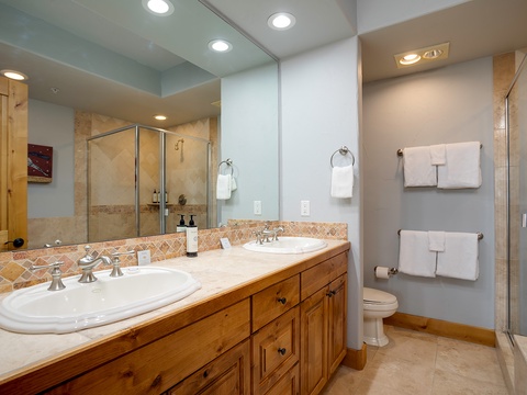 Pamper yourself in this elegant bathroom featuring dual vanities, a glass-enclosed walk-in shower, and thoughtfully arranged towels—your personal spa retreat awaits.
