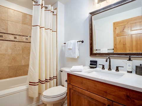 Your private bathroom features pristine white linens, a spacious vanity, and elegant tile work—offering a serene space to refresh after a day exploring the mountains.