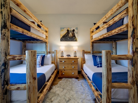 Rustic twin bunk beds create a cozy mountain retreat for your group, perfect for family gatherings or trips with friends in this charming space.