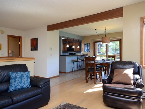 Settle into comfortable leather seating as sunlight streams through large windows, where your open-concept living, dining, and kitchen areas invite easy relaxation and memorable gatherings.